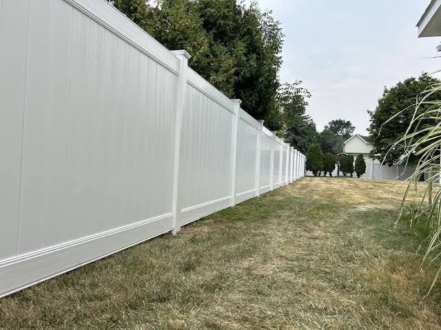 Tall white vinyl privacy fence along residential yard