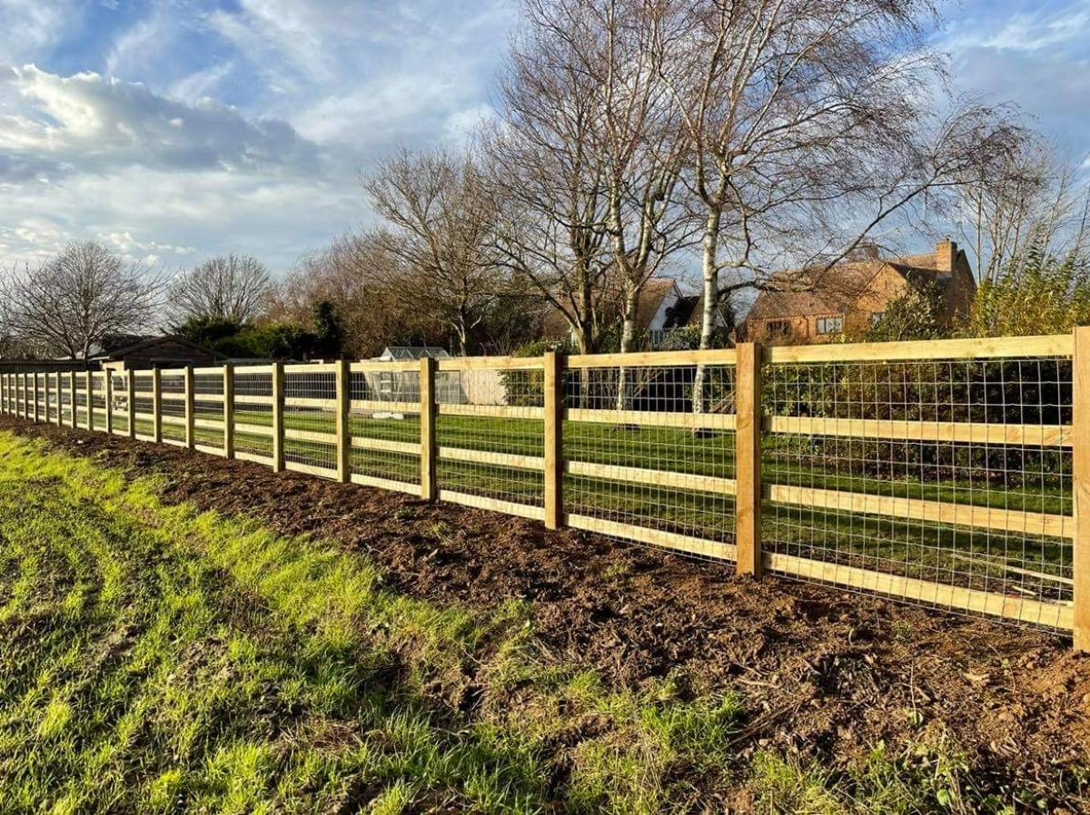 Wooden post and rail fence with wire mesh in rural landscape